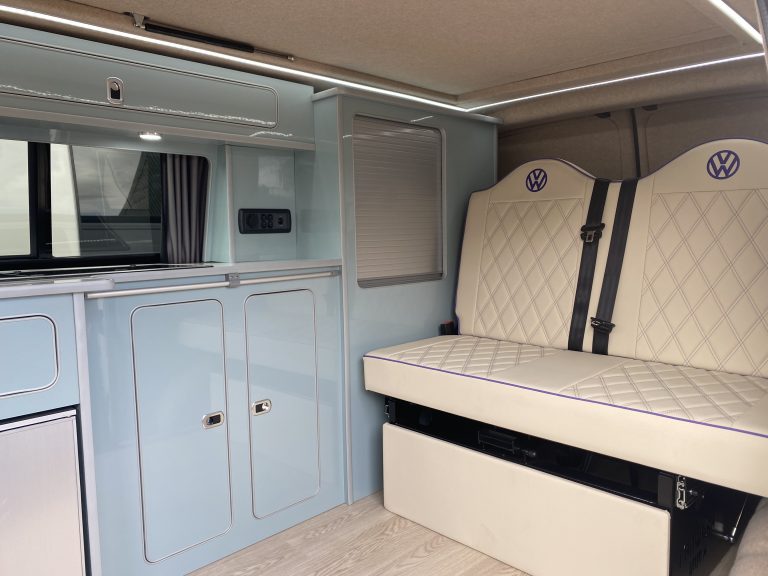 blue gloss campervan kitchen with cream quilted upholstered rock and roll bed VW logo