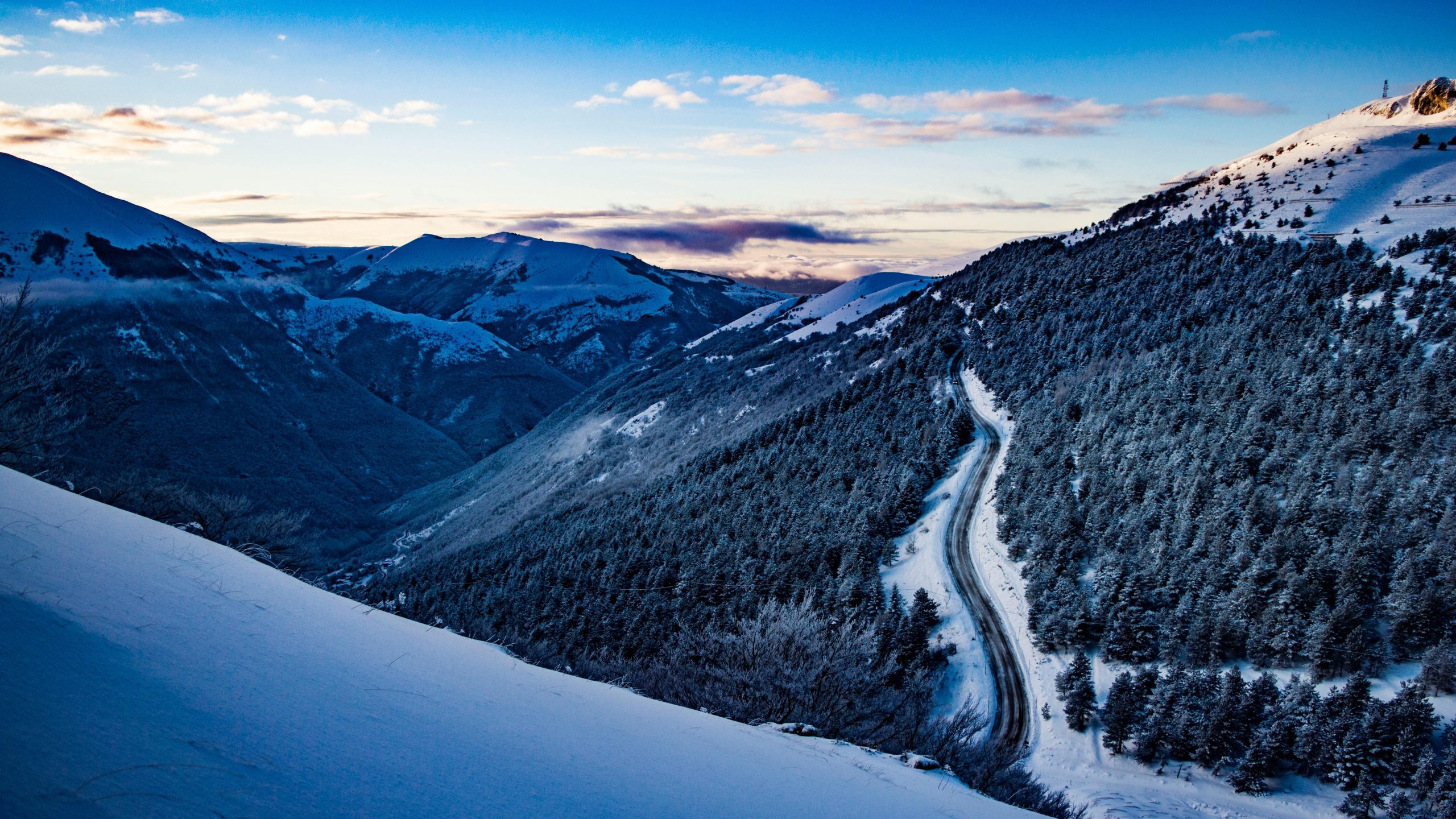 a mountain range in the snow with a road running through it